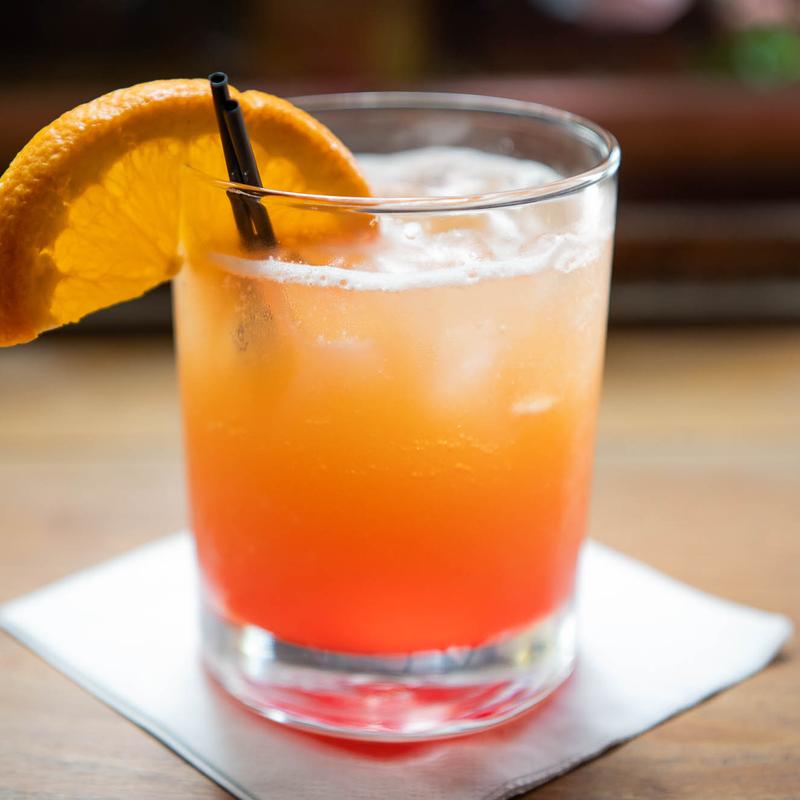 Cocktail with orange slice on napkin.
