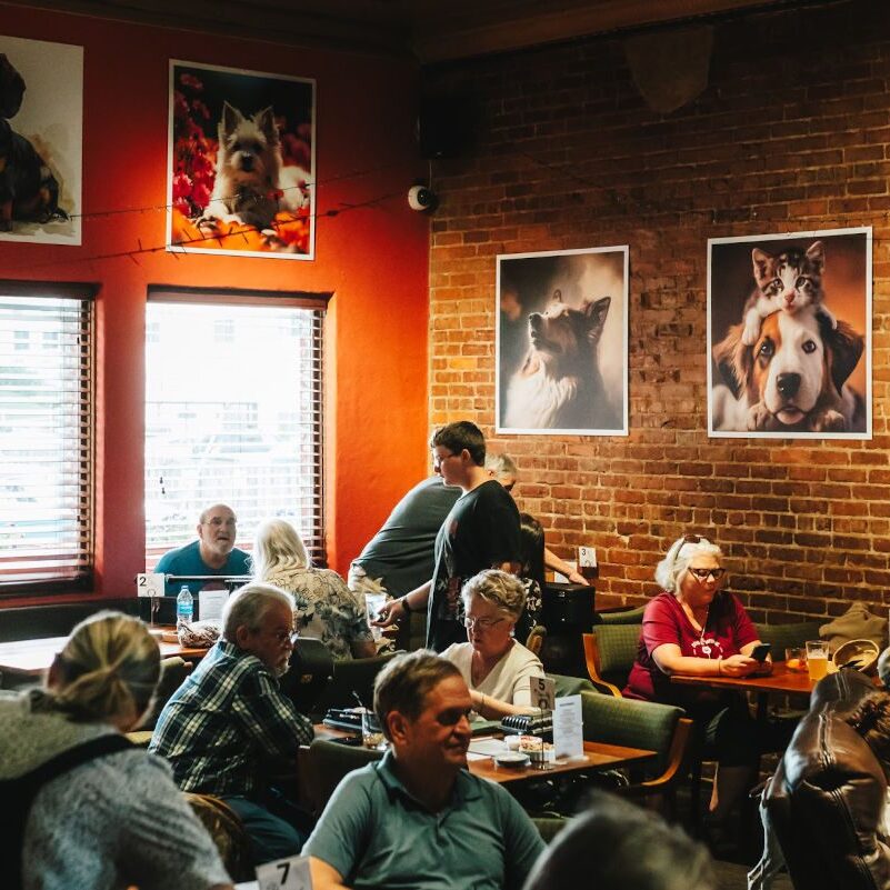 Cafe patrons seated under dog portraits.